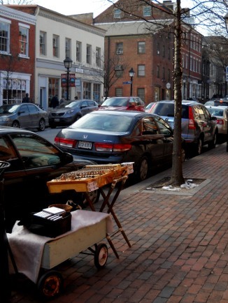 the dulcimer, set up on the street, a view past it to the parked cars and buildings behind it