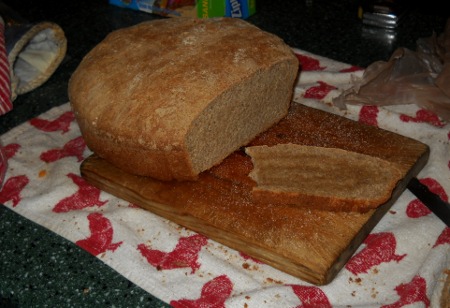 fresh, home-made bread, sliced open on the cutting board with an oiled slice waiting.