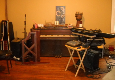 The music area in the house, the piano surrounded by instruments and gear