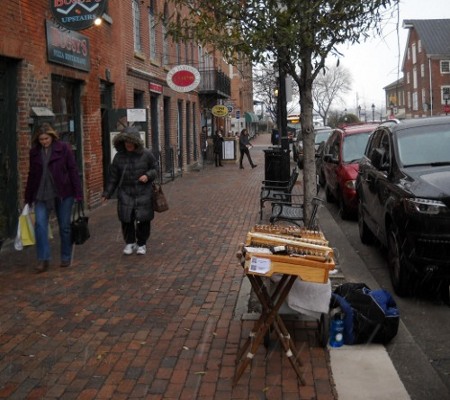 dulcimer set up on the street with snow falling and people walking in winter coats