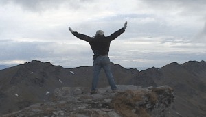 me, standing on a mountaintop facing away. arms extended out and up